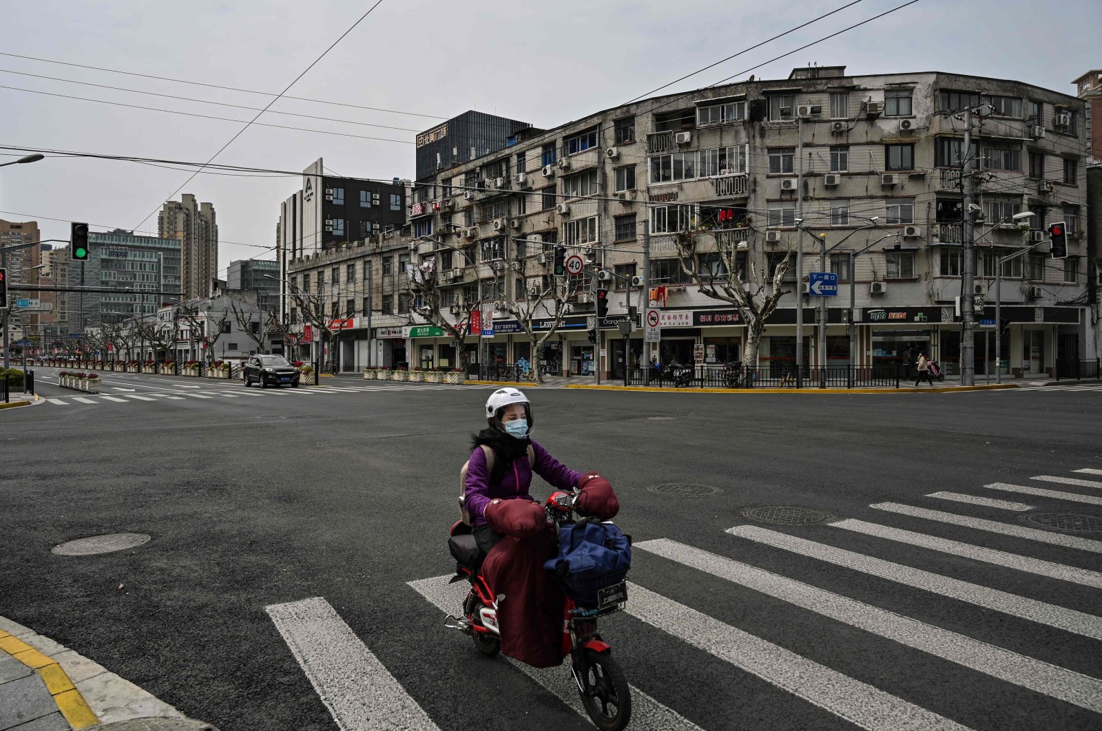 A woman drives a scooter down a quiet street in Yangpu distric, in Shanghai, China, March 28, 2022. (AFP Photo)