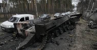 Cars drive past a destroyed Russian tank as a convoy of vehicles evacuating civilians leaves Irpin, on the outskirts of Kyiv, Ukraine, March 9, 2022. (AP Photo)