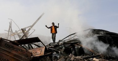 A worker reacts as he stands on the wreckage of a vehicle oil and tires store hit by Saudi-led airstrikes, in Sanaa, Yemen July 2, 2020. (Reuters Photo)