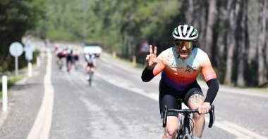 A Boostcamp participant makes the peace sign as he cycles along a road. (Photo courtesy of Leyla Yvonne Ergil)