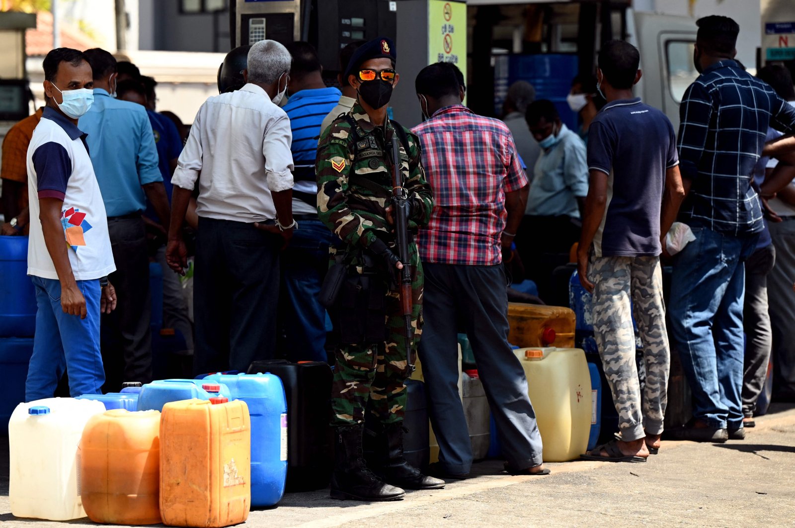 A soldier stands guard as people stand in a queue to buy diesel at a Ceylon Petroleum Corporation fuel station in Colombo, Sri Lanka, March 29, 2022. (AFP Photo)