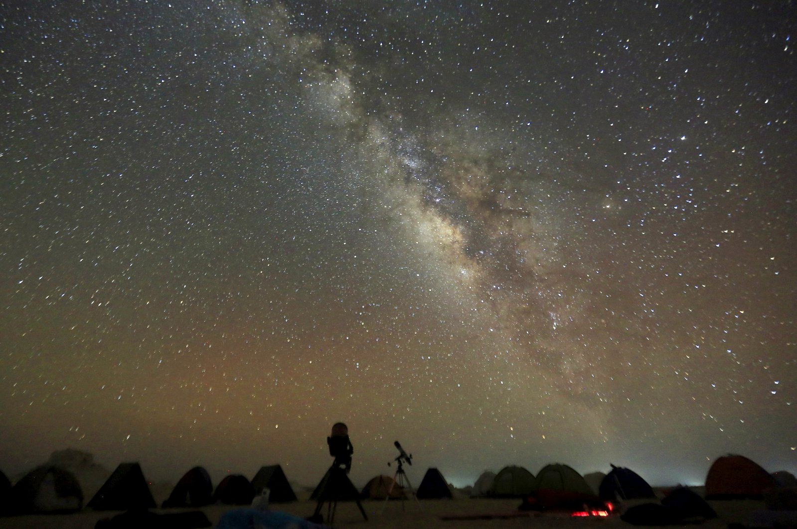 The Milky Way galaxy is seen in the night sky around telescopes and camps of people over rocks in the White Desert north of the Farafra Oasis southwest of Cairo, Egypt, May 16, 2015. (Reuters Photo)
