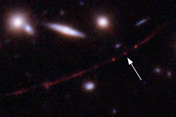This image made available by NASA on March 30, 2022, shows the star Earendel, indicated by the arrow, and the Sunrise Arc galaxy, stretching from lower left to upper right, optically bent due to a massive galaxy cluster between it and the Hubble Space Telescope, which captured the light. The mass of the galaxy cluster serves as a magnifying glass, allowing Earendel to be seen. (NASA, ESA, Brian Welch (JHU), Dan Coe (STScI); Image processing: NASA, ESA, Alyssa Pagan (STScI) via AP)