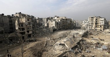 In this picture taken from the balcony of the Abdul-Hamid Khatib home, people walk through mounds of rubble that used to be high rise apartment buildings in the once opposition-held Ansari neighborhood in the eastern Aleppo, Syria, Friday, Jan. 20, 2017. (AP Photo)