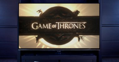 A man points a TV remote at the television displaying the &quot;Game of Thrones&quot; main title screen in this undated file photo. (Alamy Photo via Reuters)