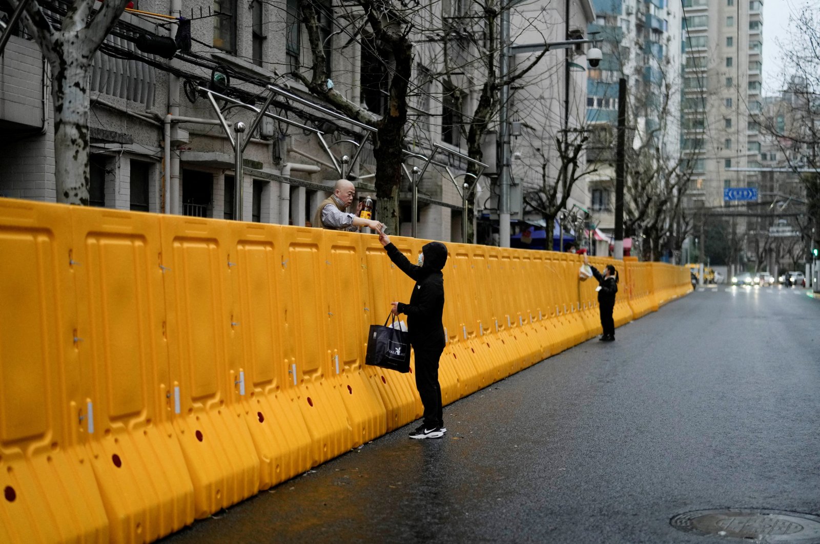 People pass food to residents over the barriers of an area under lockdown amid the coronavirus pandemic in Shanghai, China, March 25, 2022. (Reuters Photo)