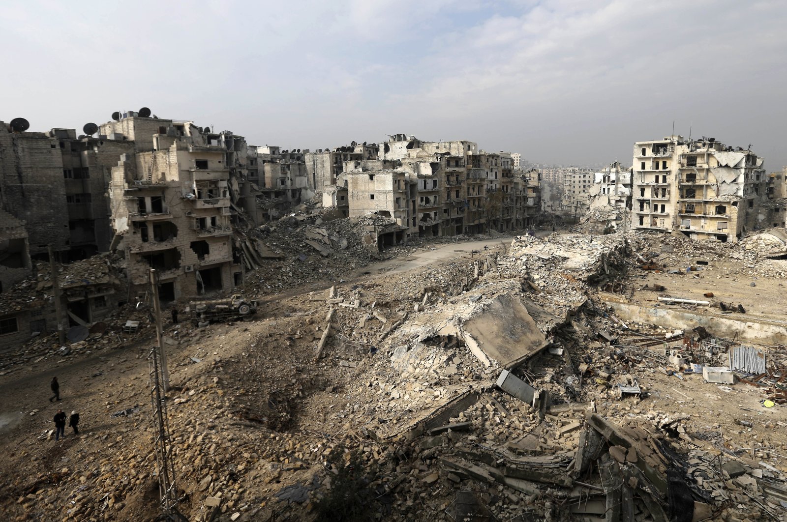 In this picture taken from the balcony of the Abdul-Hamid Khatib home, people walk through mounds of rubble that used to be high rise apartment buildings in the once opposition-held Ansari neighborhood in the eastern Aleppo, Syria, Friday, Jan. 20, 2017. (AP Photo)