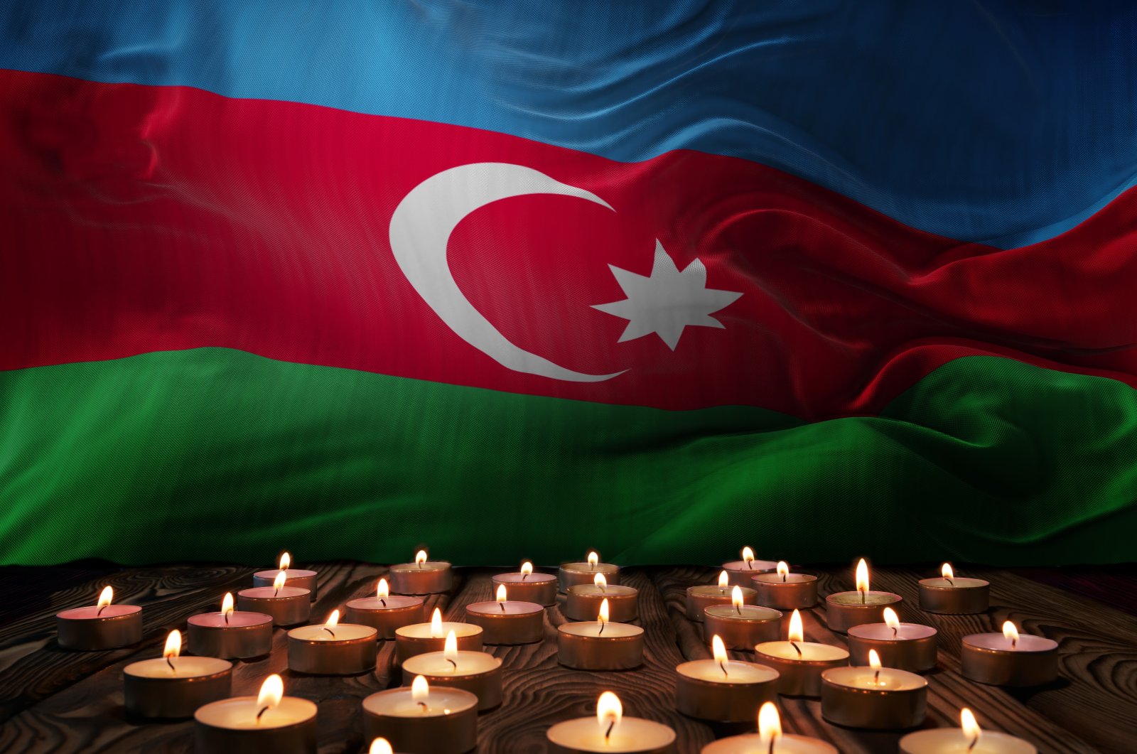 An illustration of mourning candles burning in front of the Azerbaijani national flag. (Photo by Shutterstock)