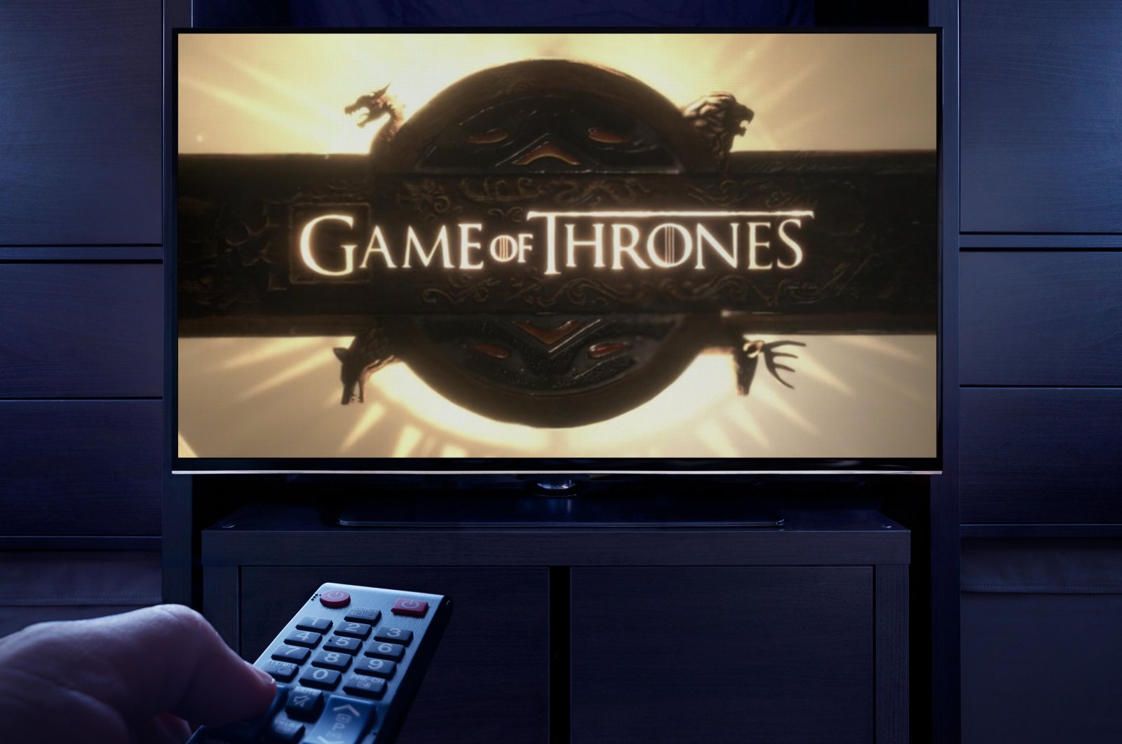 A man points a TV remote at the television displaying the &quot;Game of Thrones&quot; main title screen in this undated file photo. (Alamy Photo via Reuters)