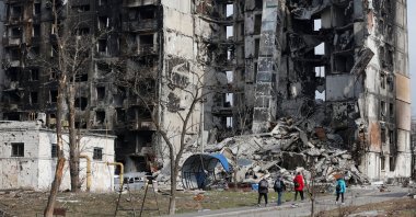 Local residents walk near an apartment building destroyed during the Ukraine-Russia conflict in the besieged southern port city of Mariupol, Ukraine, March 30, 2022. (Reuters Photo)