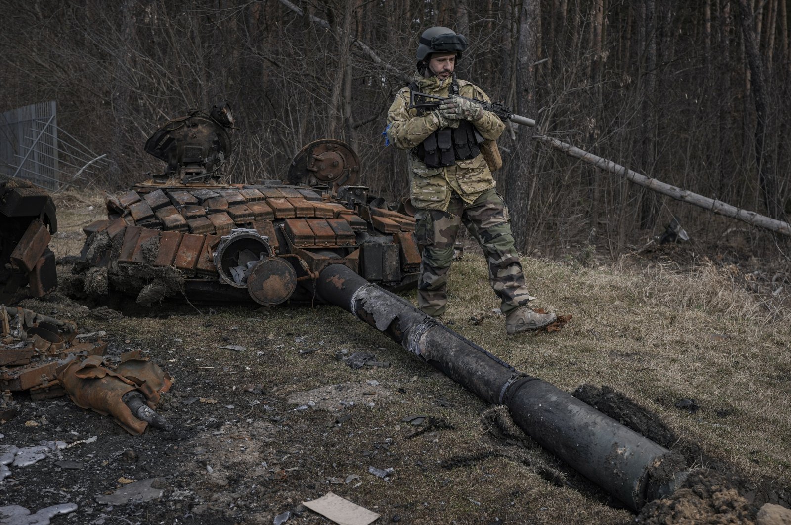 A Ukrainian service member walks next to the wreck of a Russian tank in Stoyanka, Ukraine, March 27, 2022. (AP Photo)