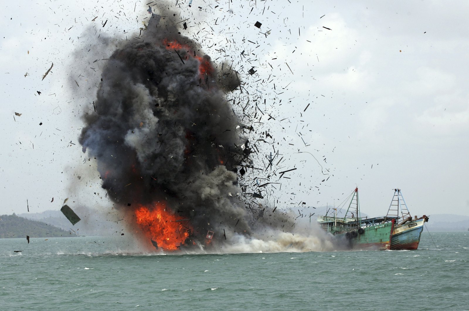 Debris flies into the air as foreign fishing boats are blown up by the Indonesian Navy off Batam Island, Indonesia, Feb. 22, 2016. (AP Photo)