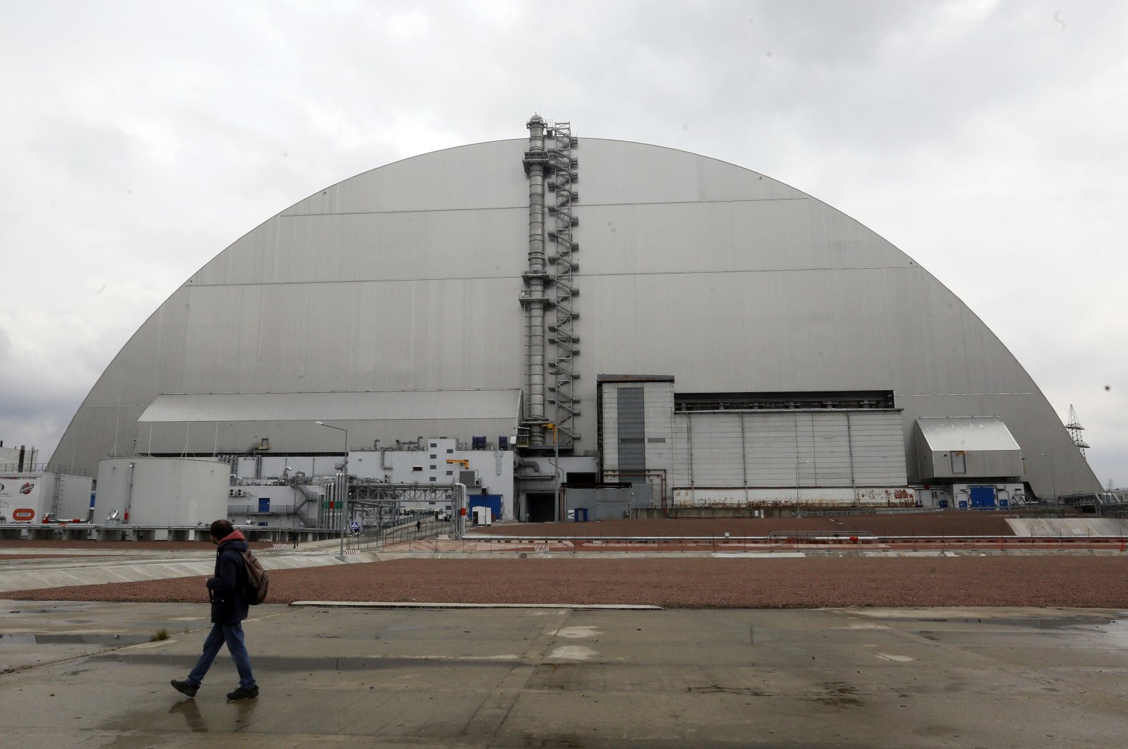 A man walks past a shelter covering the exploded reactor at the Chernobyl nuclear plant, in Chernobyl, Ukraine, April 15, 2021. (AP File Photo)