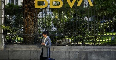 A woman looks at her phone outside a BBVA bank building in Madrid, Spain, Nov. 15, 2021. (Reuters Photo)