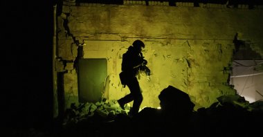 A Ukrainian special police officer walks next to a destroyed building as he patrols during night curfew in Kharkiv, Ukraine, March 27, 2022. (AP Photo)