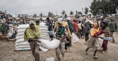 In this file photo taken on Sept. 15, 2021, Men carry a sack of wheat during a food distribution by the World Food Programme (WFP) for internally displaced people (IDP) in Debark, 90 kilometers from the city of Gondar, Ethiopia. (AFP Photo)