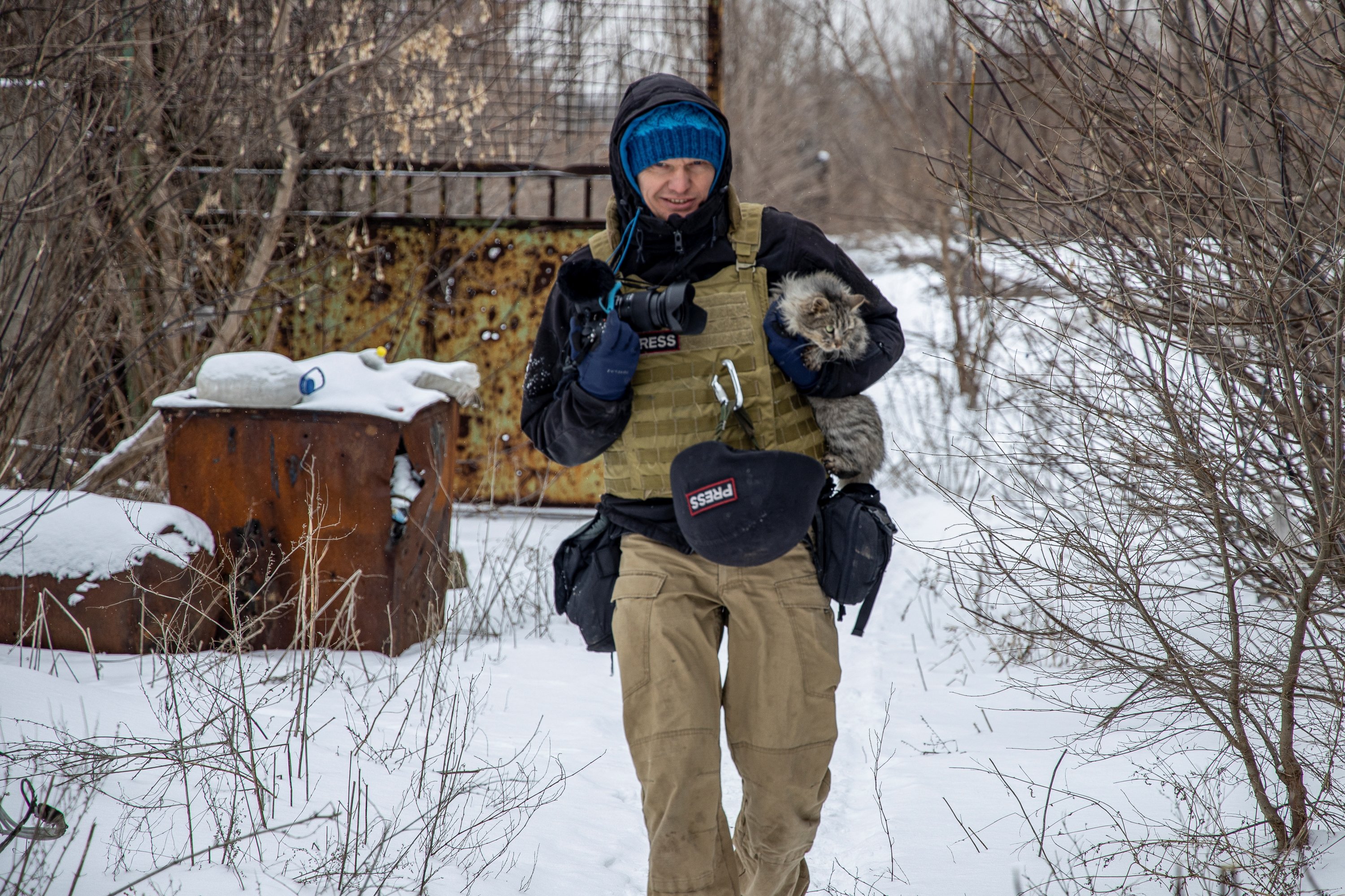 Fotografer Ukraina Maksim Levin membawa seekor kucing di dekat garis pemisahan dari separatis yang didukung Rusia di wilayah Donetsk, Ukraina, 25 Januari 2022. (Foto Reuters)
