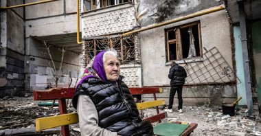A woman looks on as she sits on a bench outside a destroyed building in the eastern Ukraine city of Kharkiv on April 2, 2022. (AFP Photo)