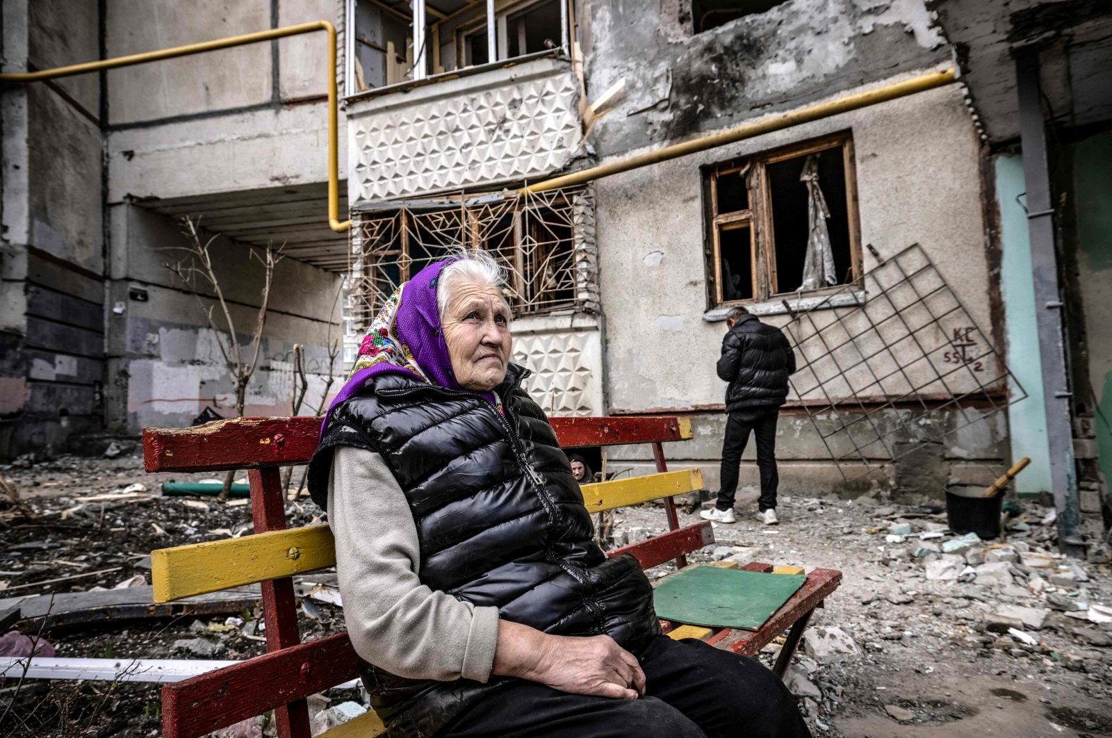 A woman looks on as she sits on a bench outside a destroyed building in the eastern Ukraine city of Kharkiv on April 2, 2022. (AFP Photo)