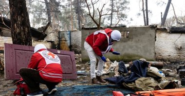 Red Cross staff help a local resident as the humanitarian organization delivers food and first aid to residents that have been affected by fighting during Russia&#039;s invasion of Ukraine, in Irpin, April 1, 2022. (Reuters via International Committee of the Red Cross)