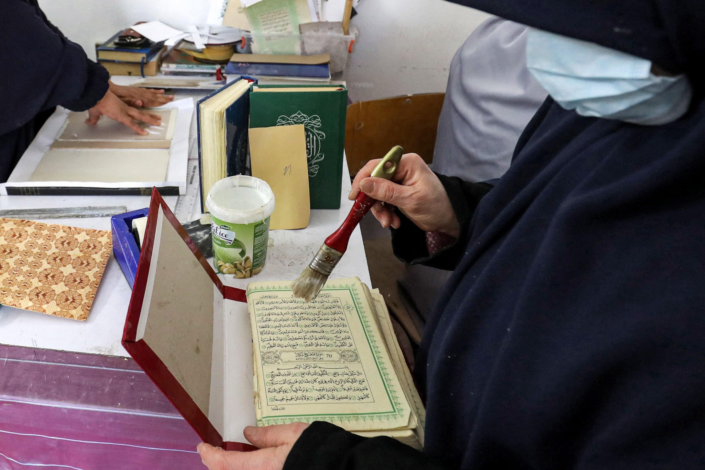 Seorang wanita bersiap untuk menjilid sampul keras sebuah volume Al-Qur'an, kitab suci Islam, selama lokakarya restorasi salinannya di ibu kota Libya, Tripoli, 22 Maret 2022. (AFP Photo)