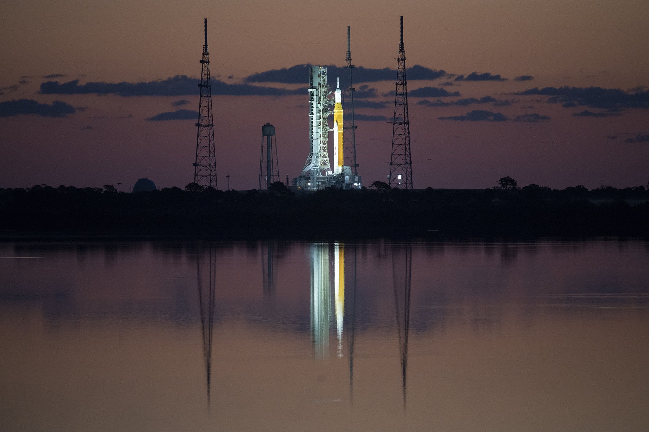 Roket Space Launch System (SLS) NASA dengan pesawat ruang angkasa Orion terlihat saat matahari terbit di atas peluncur bergerak di Launch Complex 39B di Kennedy Space Center NASA di Cape Canaveral, Florida, AS, 4 April 2022. (NASA via AP)