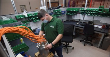 An employee at Advanced Electric Machines works on test models of a motor for an electric vehicle that does not include either rare earth magnets or copper, and uses electrical steel and aluminum instead, in Washington, Britain, November 26, 2021. (Reuters Photo)
