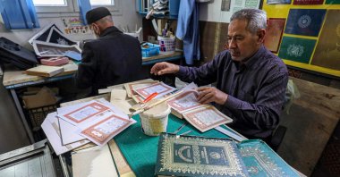 A Libyan restorer of the Quran, Khaled al-Drebi (R), assembles pages to be glued into a volume during a workshop on the restoration of copies of Islam&#039;s holy book, in Libya&#039;s capital Tripoli, March 22, 2022. (AFP Photo)