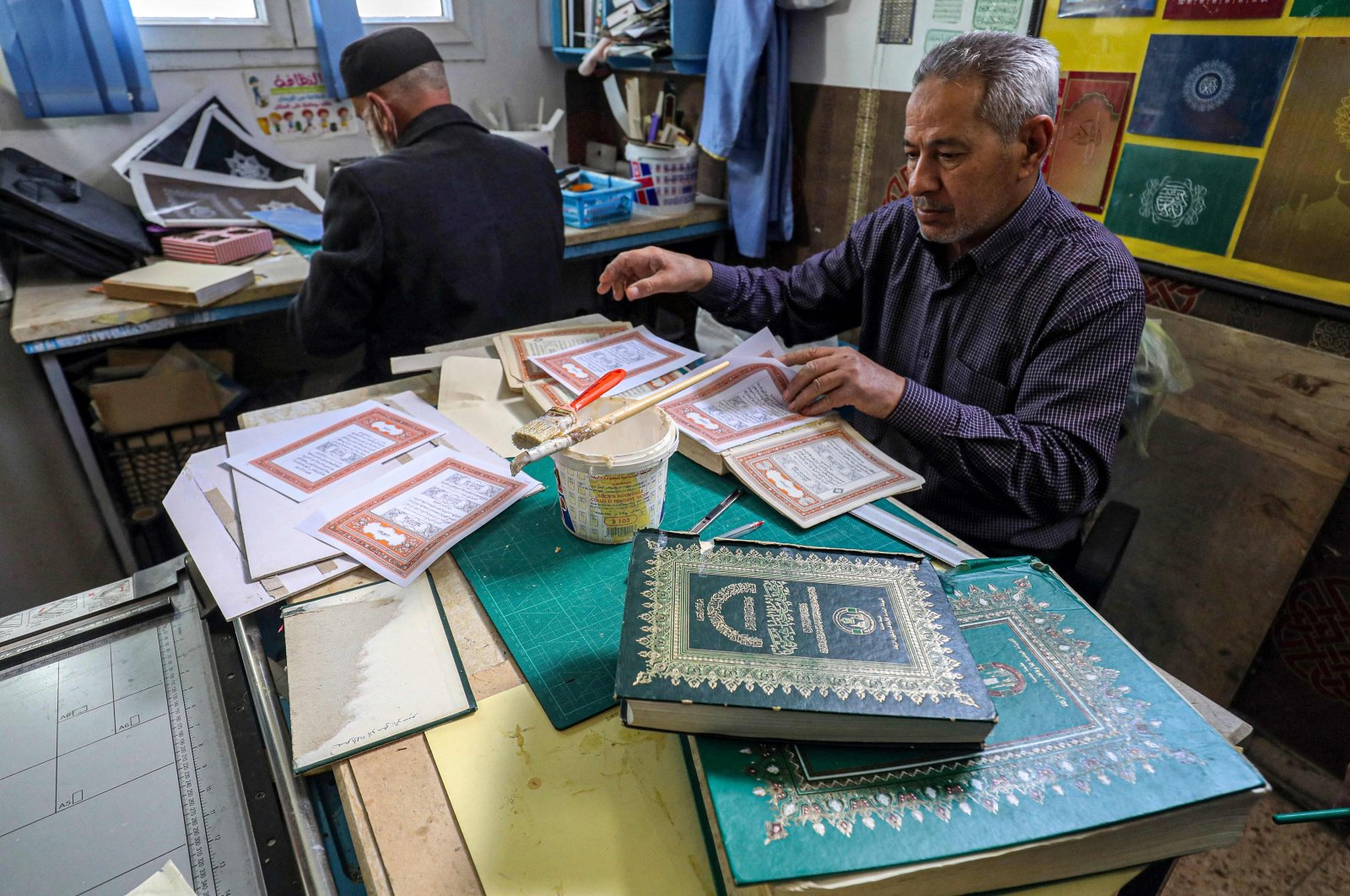 A Libyan restorer of the Quran, Khaled al-Drebi (R), assembles pages to be glued into a volume during a workshop on the restoration of copies of Islam&#039;s holy book, in Libya&#039;s capital Tripoli, March 22, 2022. (AFP Photo)