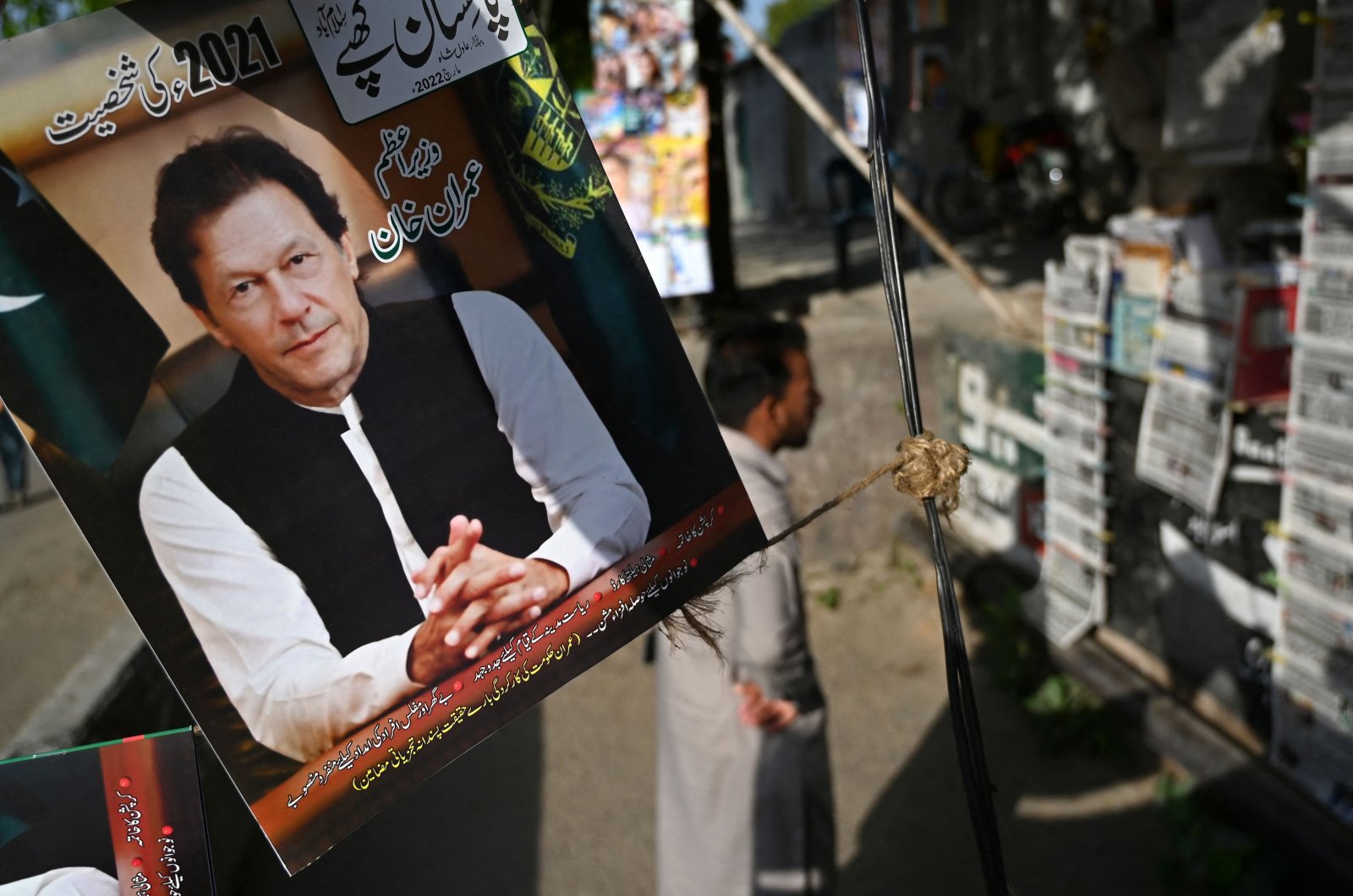 A resident stands beside a picture of Pakistan&#039;s Prime Minister Imran Khan as he looks at the morning newspapers displayed for sale at a roadside stall in Islamabad, Pakistan, April 4, 2022. (AFP Photo)