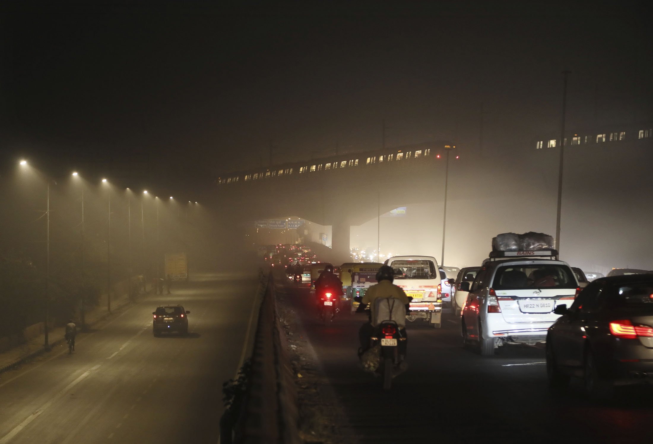 Para komuter berkendara di jalan yang diselimuti kabut asap di New Delhi, India, 5 November 2020. (AP Photo)