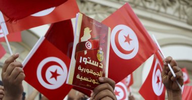 A demonstrator holds a copy of the Tunisian constitution, during a protest against Tunisian President Kais Saied in Tunis, Tunisia, Sunday, Sept. 26, 2021. (AP File Photo)