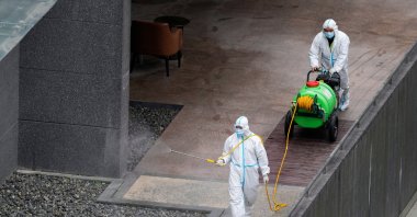 Workers in protective suits spray disinfectant at a community, during the lockdown to curb the spread of the coronavirus in Shanghai, China, April 5, 2022. (Reuters Photo)