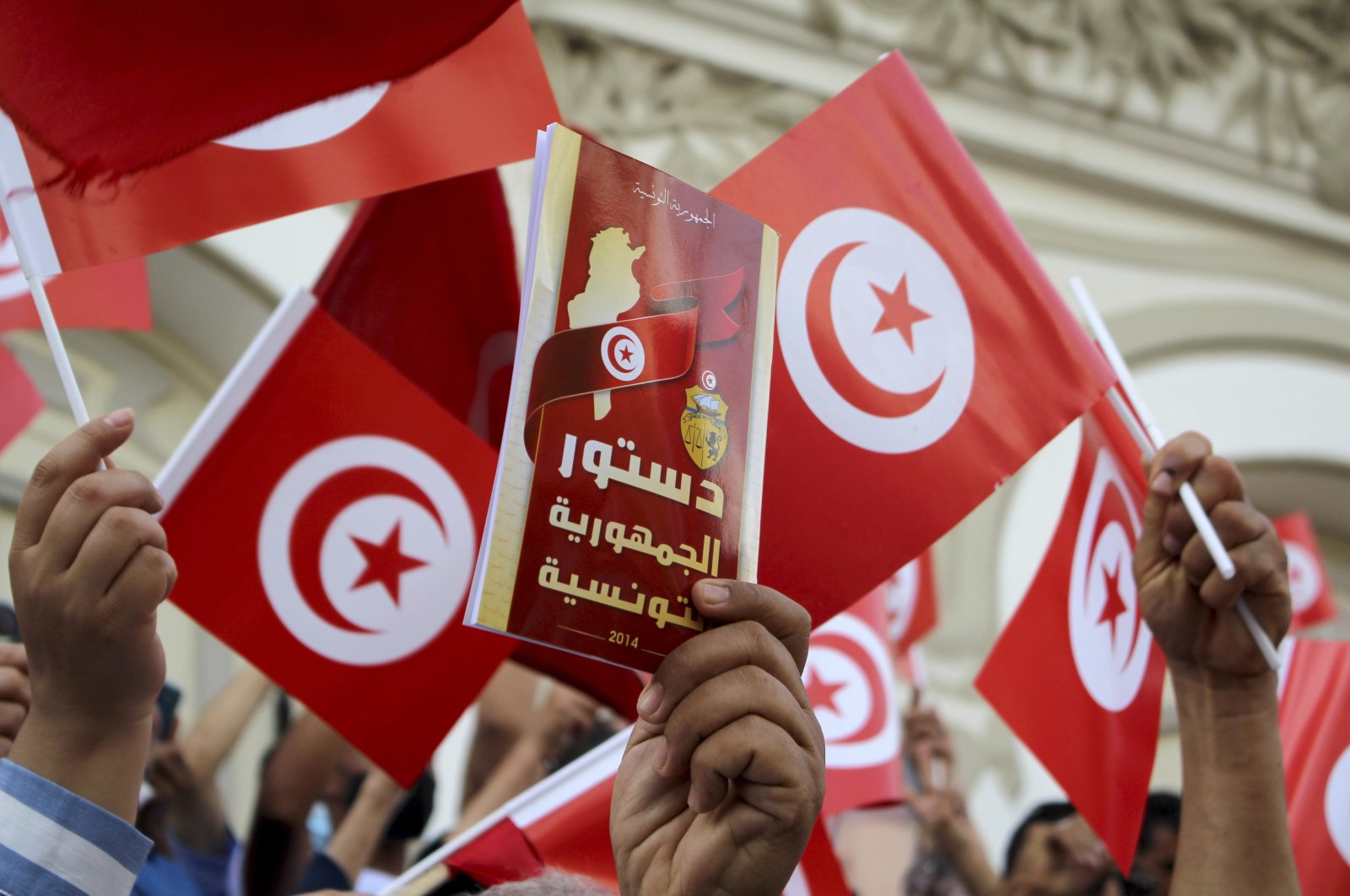 A demonstrator holds a copy of the Tunisian constitution, during a protest against Tunisian President Kais Saied in Tunis, Tunisia, Sunday, Sept. 26, 2021. (AP File Photo)