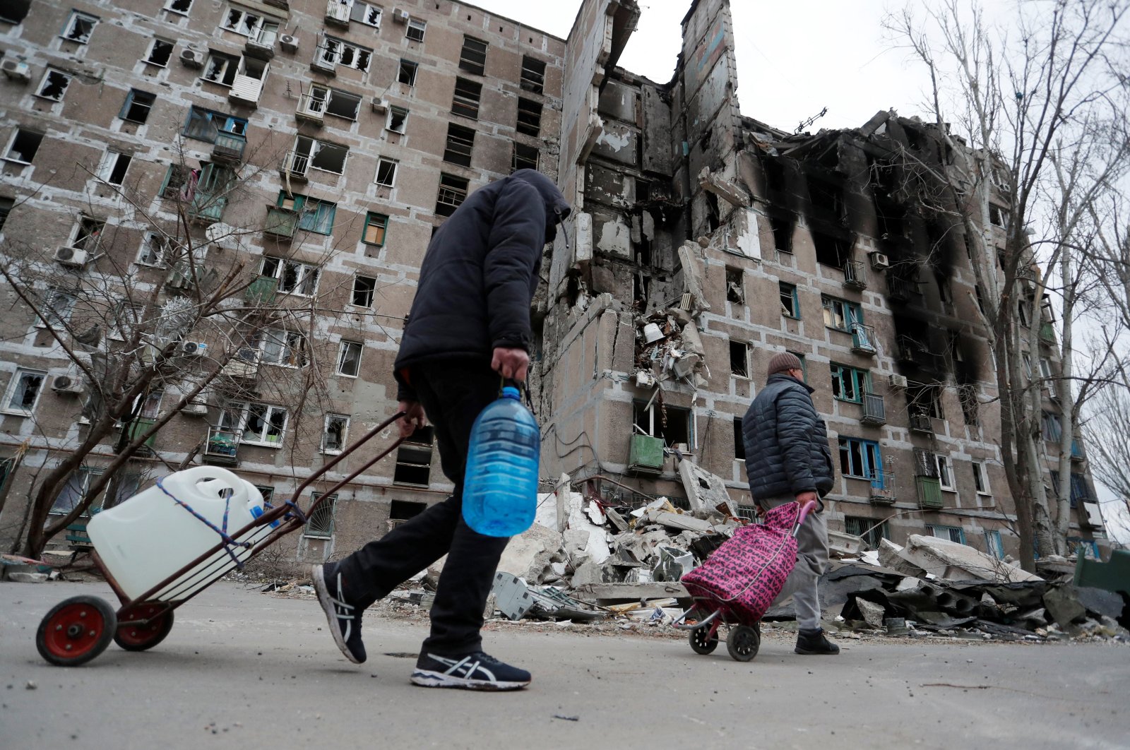 Local residents walk past an apartment building damaged during the Ukraine-Russia conflict in the southern port city of Mariupol, Ukraine, April 4, 2022. (REUTERS Photo)