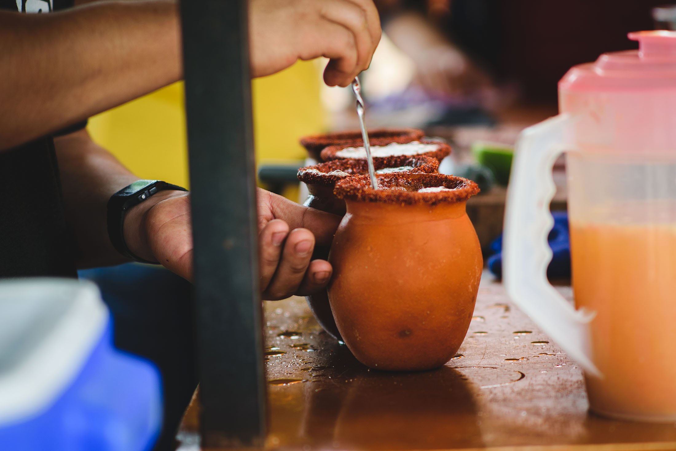Mexican man pours lemon for a typical Tequila cocktail named cantarito. (Shutterstock Photo)