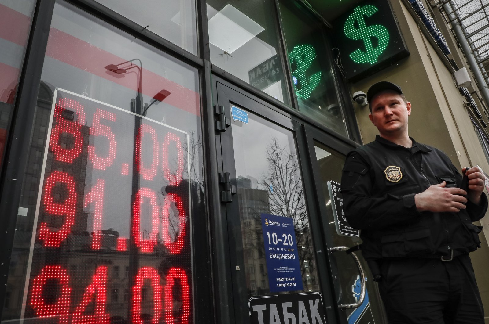 A security guard stands in front of an exchange office with a screen displaying the exchange rates of the euro and U.S. dollar to Russian rubles in Moscow, Russia, March 31, 2022. (EPA Photo)