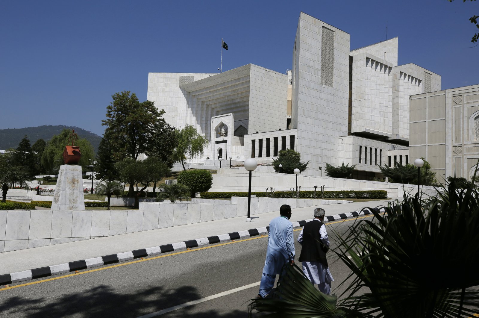 People walk past the Supreme Court where a petition hearing to dissolve parliament by the country&#039;s prime minister is taking place in Islamabad, Pakistan, April 4, 2022. (AP Photo)