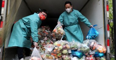 Workers wearing protective gear sort bags of vegetables and groceries on a truck to distribute them to residents at a residential compound, during the lockdown to curb the coronavirus outbreak in Shanghai, China, April 5, 2022. (China Daily via Reuters)