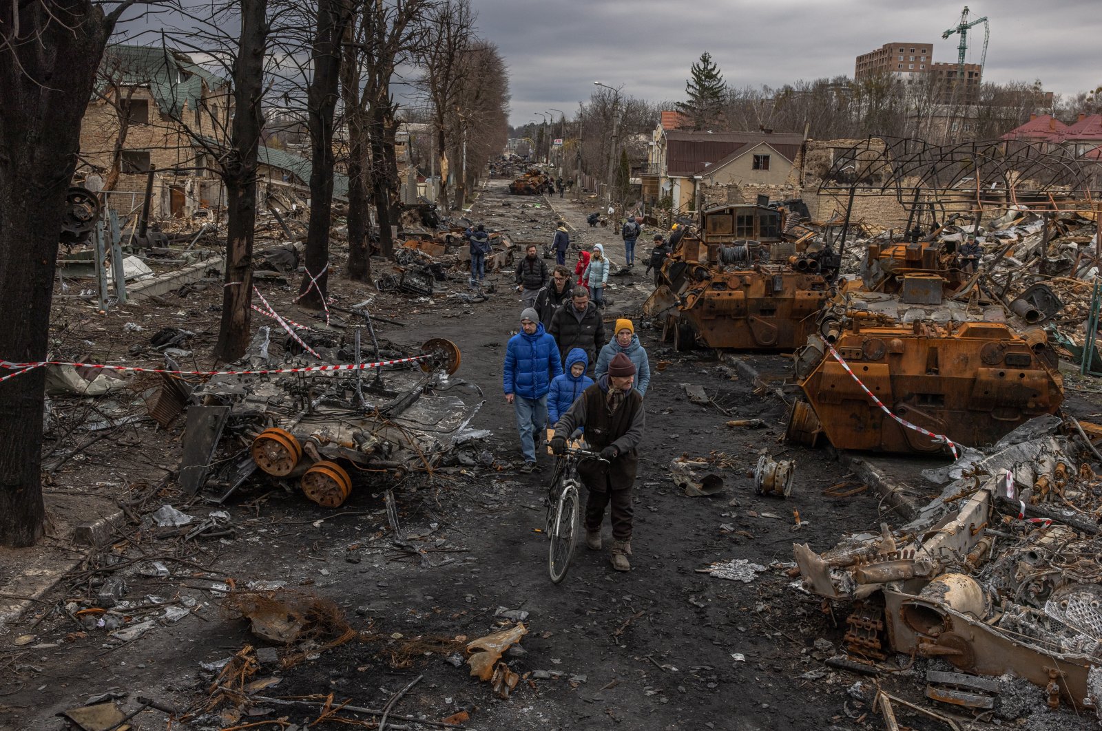 Residents walk past destroyed Russian military machinery on the street in Bucha, the town which was retaken by the Ukrainian army, northwest of Kyiv, Ukraine, April 6, 2022. (EPA Photo)