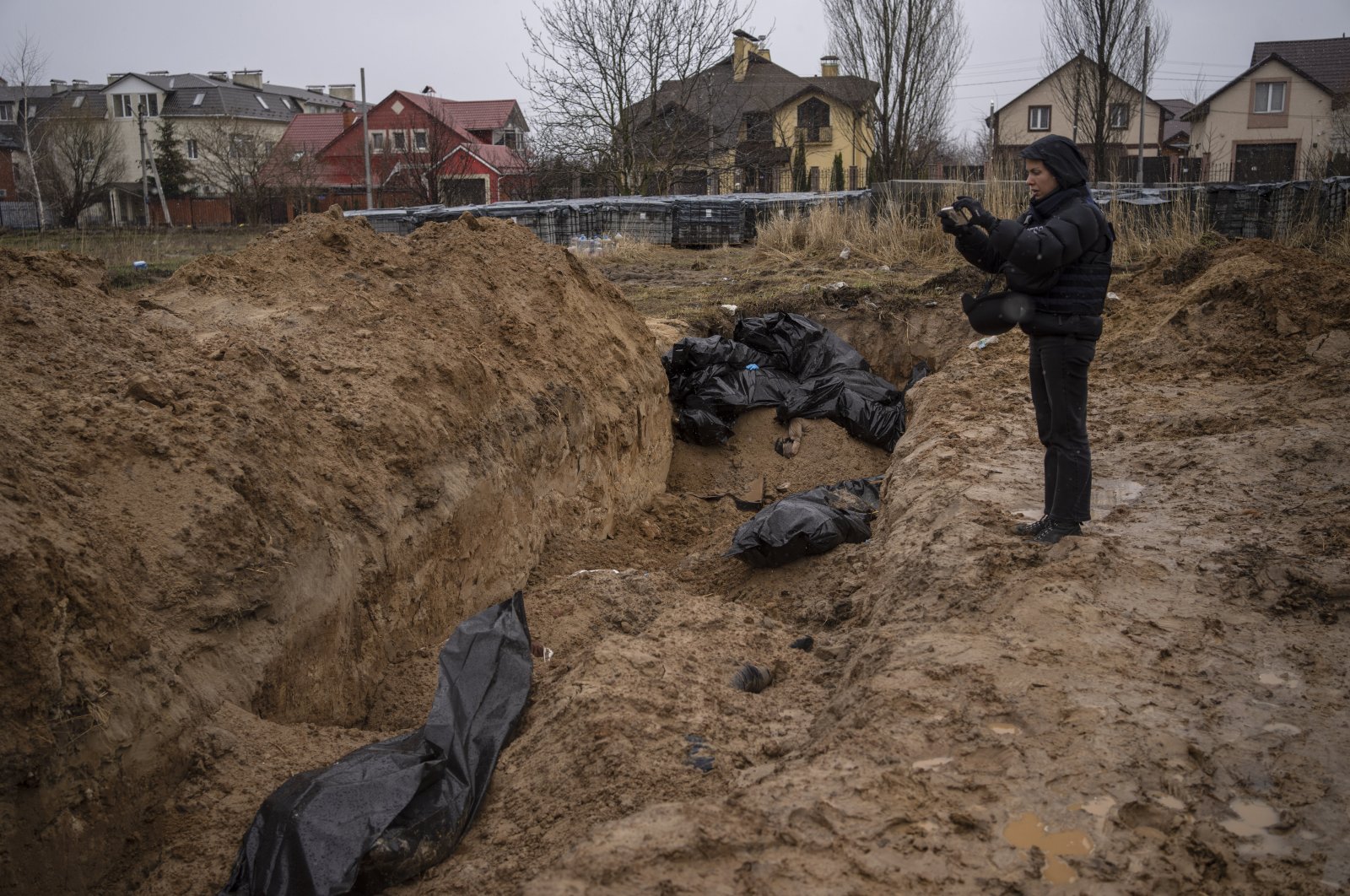 A journalist takes video of a mass grave in Bucha, on the outskirts of Kyiv, Ukraine, Sunday, April 3, 2022. (AP Photo)