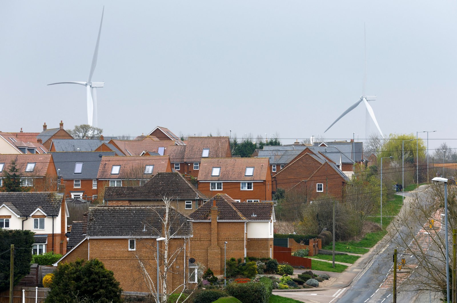 Wind turbines are seen behind houses in Burton Latimer, Britain, March 30, 2022. (Reuters Photo)