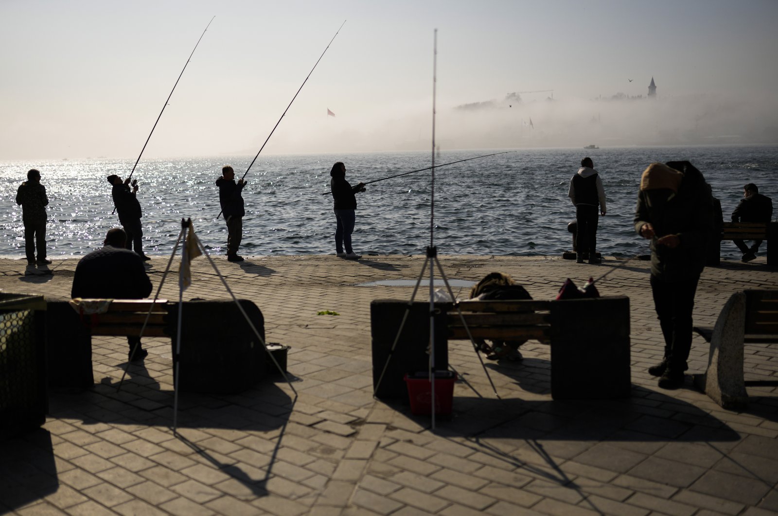 Fishermen cast their lines into the Bosporus at a promenade during a foggy morning in Karaköy, Istanbul, Turkey, April 6, 2022. (AP Photo)