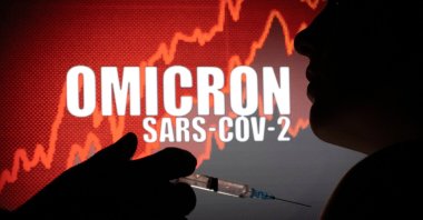 People pose with syringe with needle in front of displayed words &quot;OMICRON SARS-COV-2&quot;, December 11, 2021. (Reuters Photo)