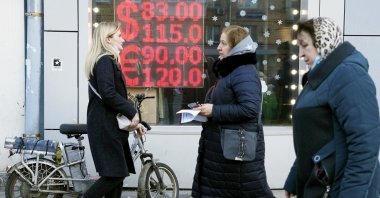 People walk past a currency exchange office screen displaying the exchange rates of the U.S. dollar and euro to Russian rubles, Moscow, Russia, Feb. 28, 2022. (AP File Photo)