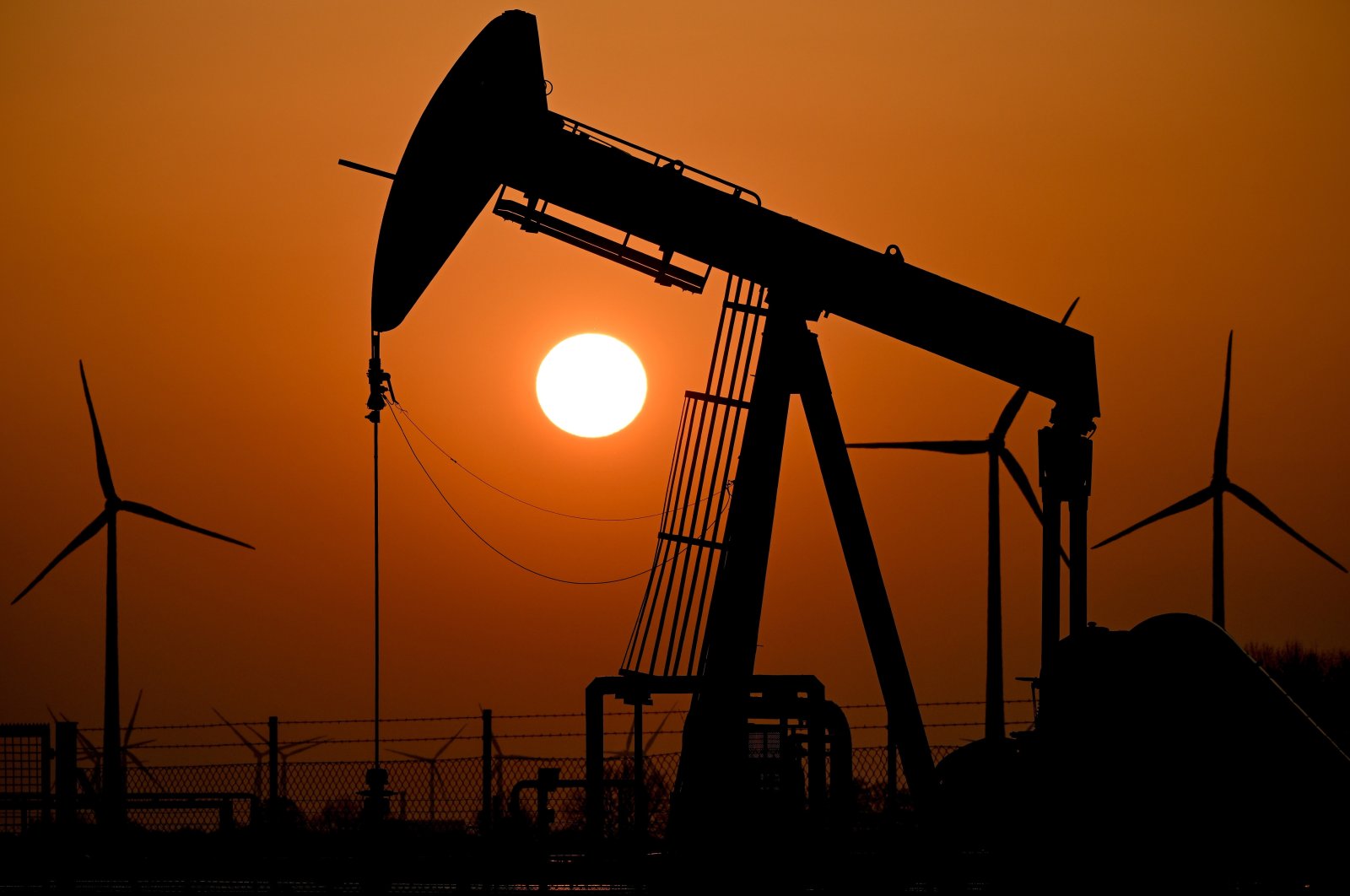 A pump jack conveys crude oil as the sun sets behind an oil field near the German-Durch border in Emlichheim, Germany, March 22, 2022. (EPA Photo)