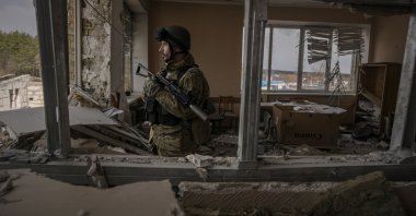 A Ukrainian service member stands in a heavily damaged building in Stoyanka, Ukraine, March 27, 2022. (AP Photo)
