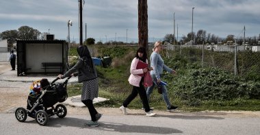 Ukrainian refugees (R) walk next to a migrant woman from Afghanistan with her baby (L) at Serres refugee camp, northern Greece, April 4, 2022. (AFP Photo)
