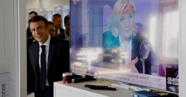 French President Emmanuel Macron visits France Inter's office, next to a TV screen displaying French far-right party Rassemblement National (RN) presidential candidate Marine Le Pen (R), after the France Inter 7/9 radio broadcast at the Maison de la Radio in Paris, France, April 4, 2022. (AFP Photo)