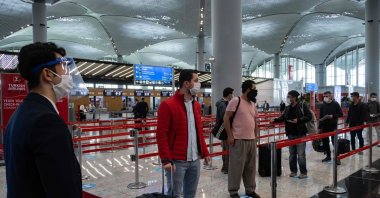 Passengers wearing protective face masks wait to be checked in at Istanbul Airport on the first day of the resumption of domestic flights after a pause due to the pandemic, in Istanbul, Turkey, June 1, 2020. (AFP Photo)